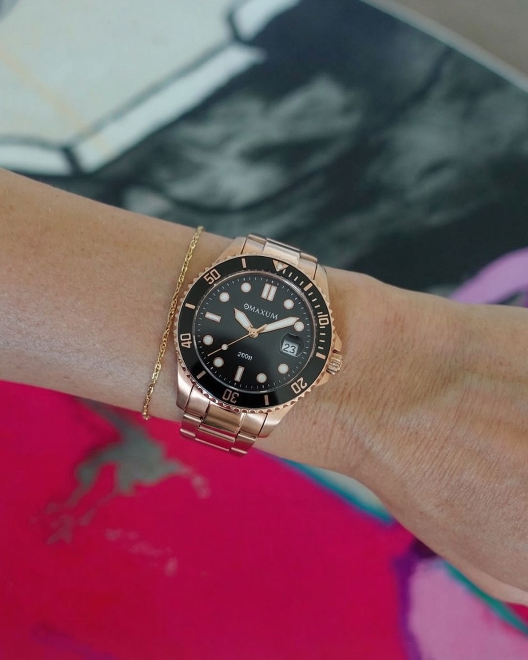Maxum Liberty Rose gold watch with black dial on a wrist against a colourful background