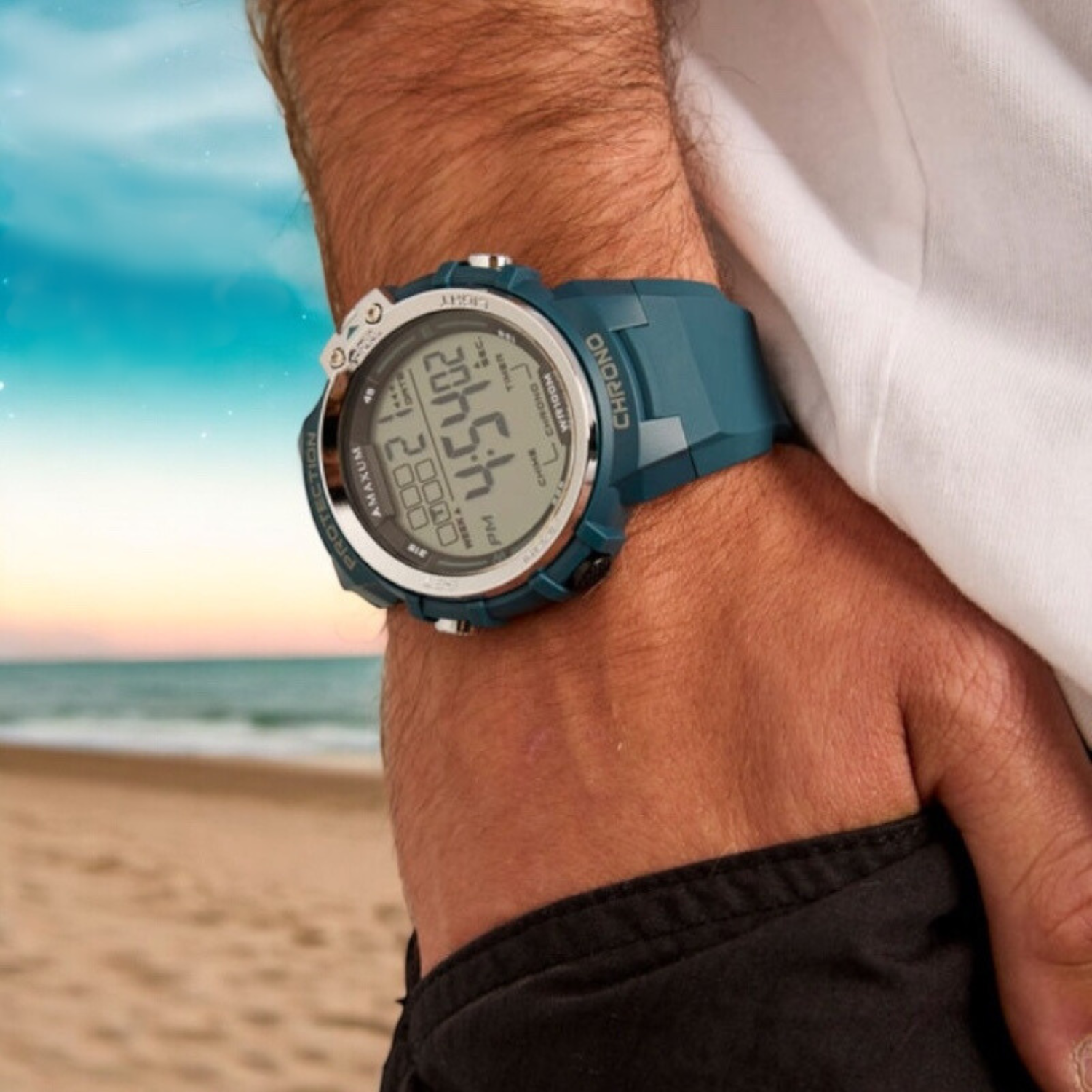 Maxum Explorer Blue Digital Watch with a blue resin strap, featuring a digital display with silver accent on wrist shot with beach background