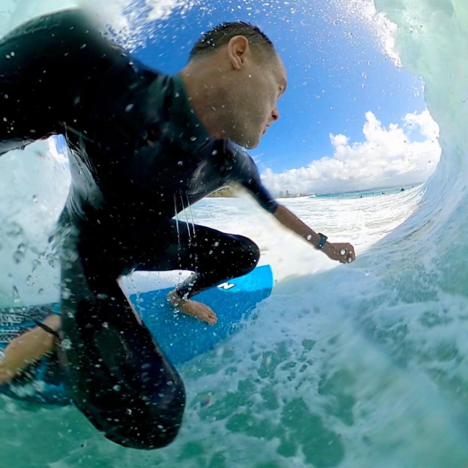 Person surfing inside a wave with clear blue water and sky wearing Maxum Maverick Blue Analogue Digital Watch with a silver and blue-tone case, a digital display, and a blue resin strap.