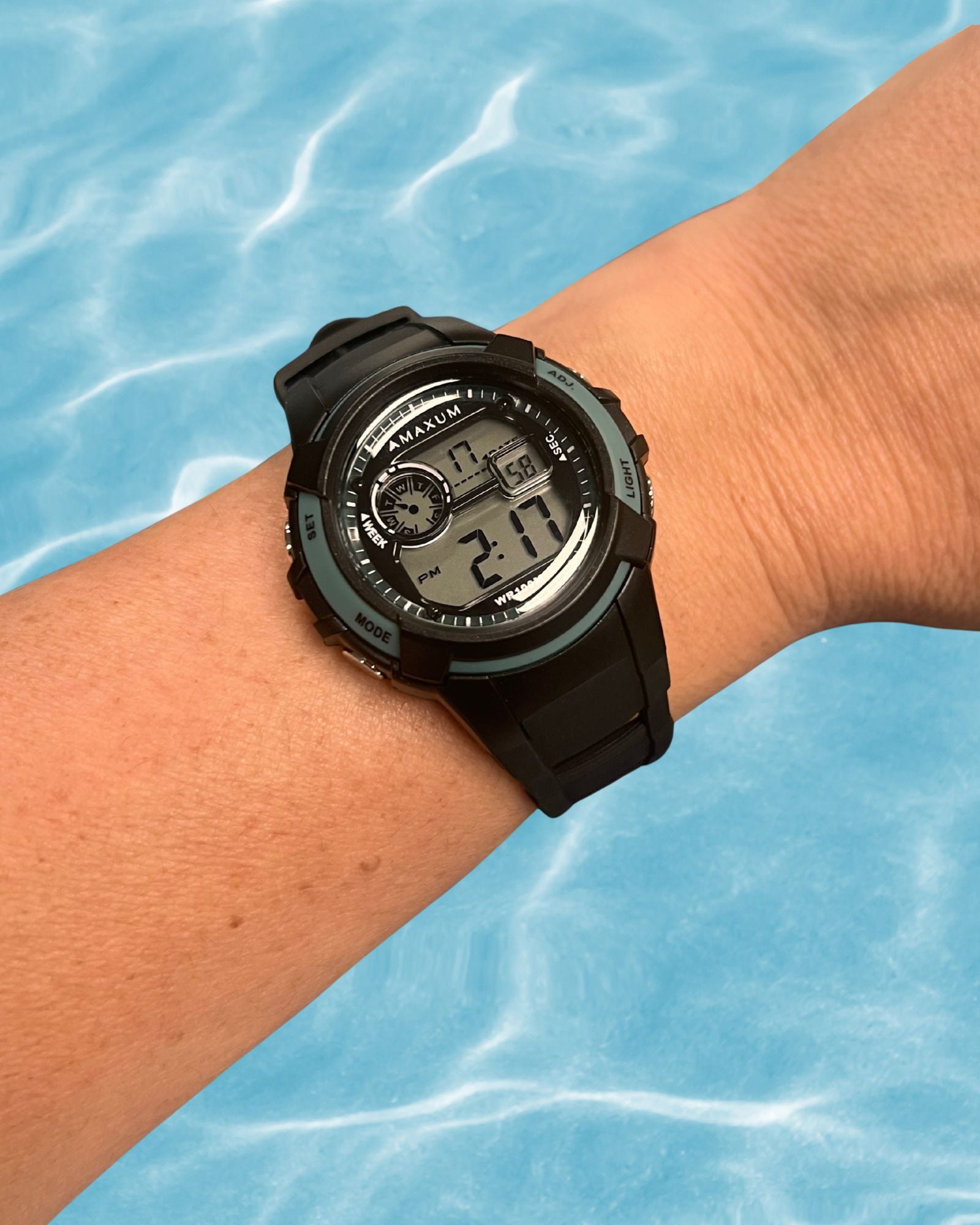 Maxum Button digital watch with a black resin strap and black case, featuring blue accents and a digital display on wrist