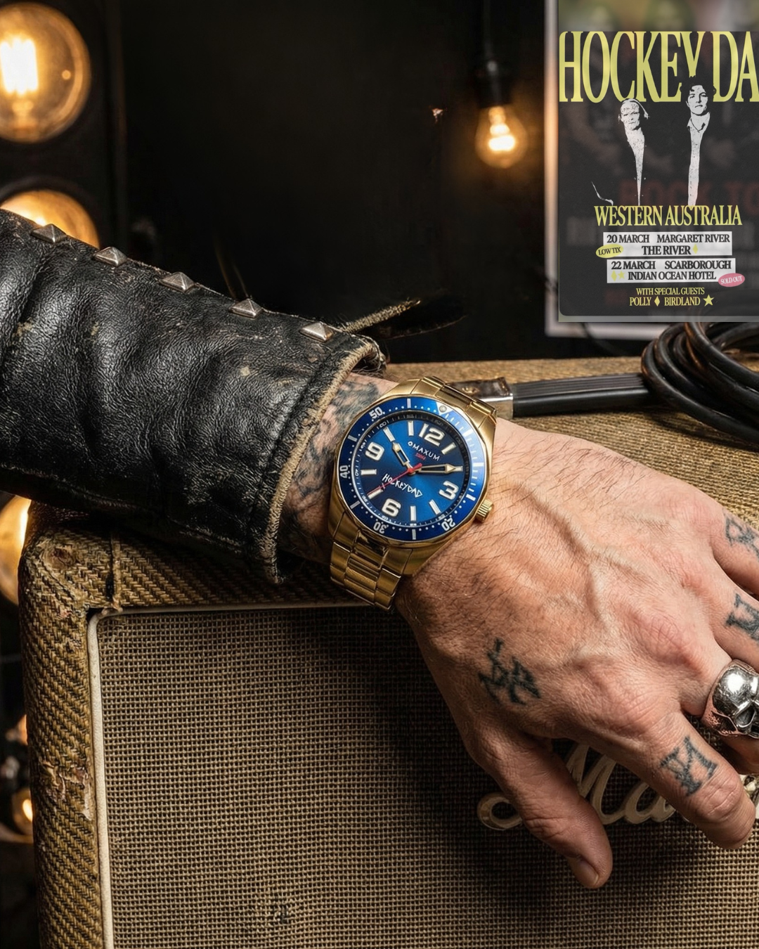 Hand wearing Hockey Dad x Maxum collab  gold watch with blue face on a textured surface, with a background featuring a gig poster 'Hockey Dad'.