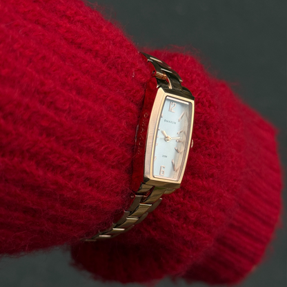 Maxum Fanta Reissue Rectangular rose gold-tone rectangular analogue watch with a white dial and a stainless steel bracelet. Close up on women's wrist wearing a red jumper