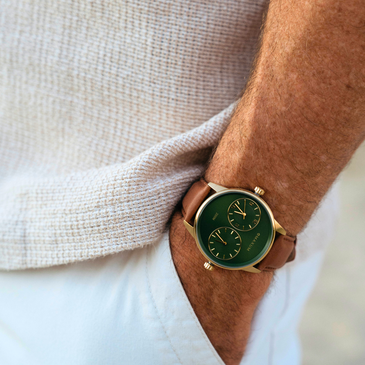 Maxum Taylor Steele Collaboration Watch with a green dial, gold-tone case, and brown leather band,  on a wrist, wearing a light-colorued shirt.